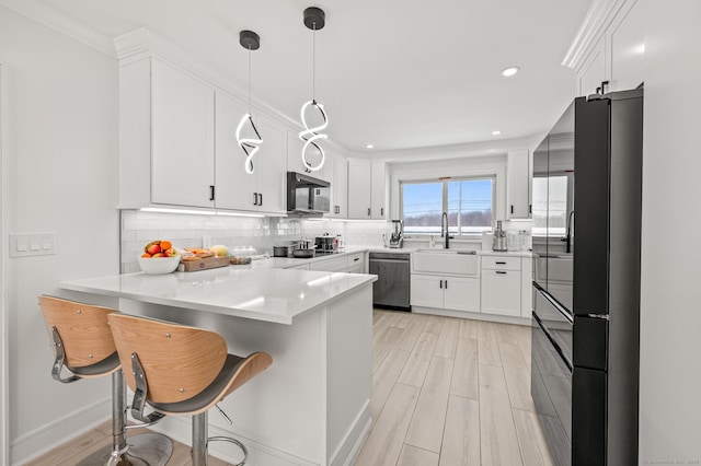 kitchen with decorative backsplash, dishwasher, a peninsula, white cabinetry, and a sink