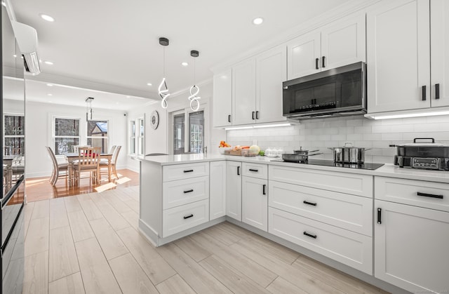 kitchen with decorative backsplash, a peninsula, wood tiled floor, black electric stovetop, and white cabinetry