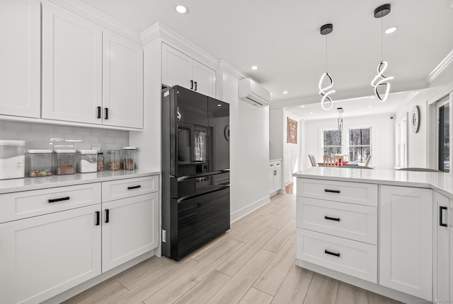 kitchen with tasteful backsplash, white cabinets, ornamental molding, freestanding refrigerator, and a wall mounted air conditioner