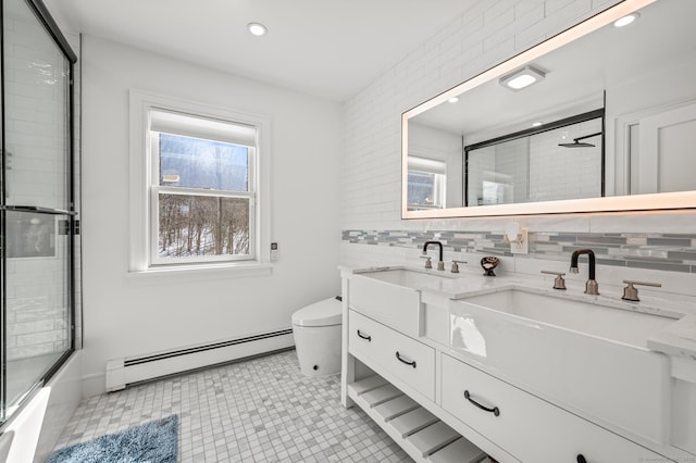 full bath with double vanity, tasteful backsplash, a baseboard radiator, toilet, and a sink