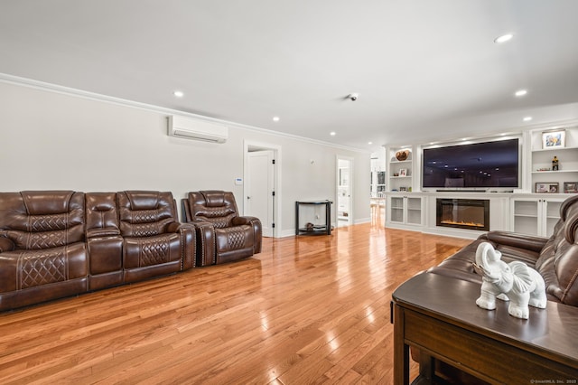 living area featuring recessed lighting, a wall mounted AC, light wood-type flooring, a glass covered fireplace, and crown molding