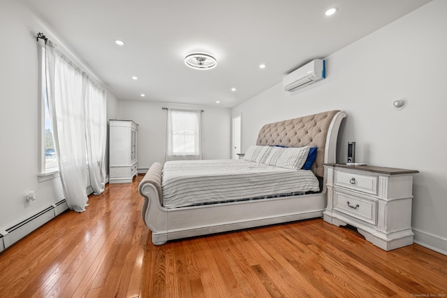 bedroom with a baseboard heating unit, recessed lighting, a wall mounted air conditioner, and light wood-style flooring