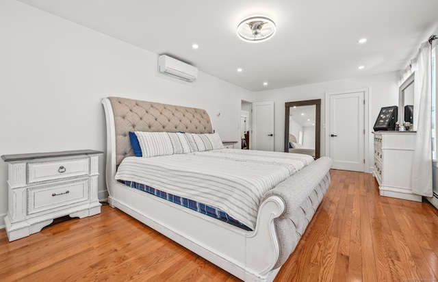 bedroom with light wood-type flooring, a wall mounted air conditioner, and recessed lighting