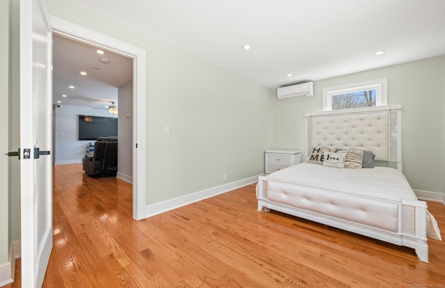 bedroom with light wood-type flooring, baseboards, and a wall mounted air conditioner