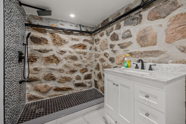 full bath with marble finish floor, a tile shower, and vanity