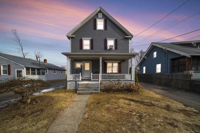 traditional home featuring a porch and fence