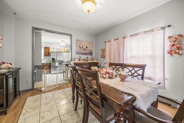 dining area with a baseboard radiator and light wood finished floors