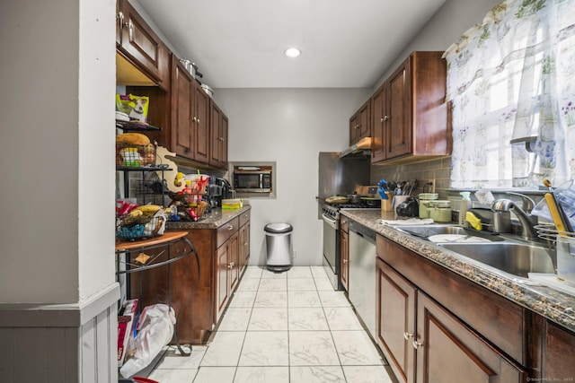 kitchen with stainless steel appliances, dark countertops, backsplash, a sink, and under cabinet range hood