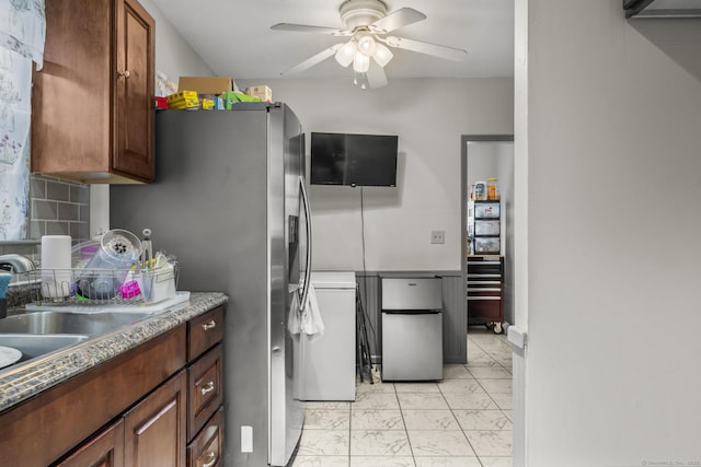 kitchen featuring ceiling fan, a sink, marble finish floor, backsplash, and freestanding refrigerator