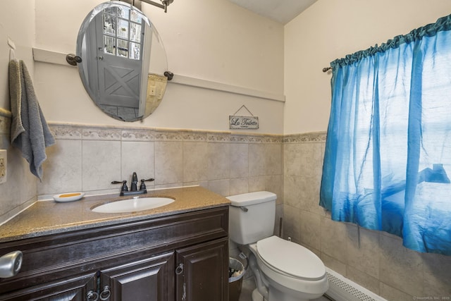 bathroom with toilet, a wainscoted wall, tile walls, and vanity