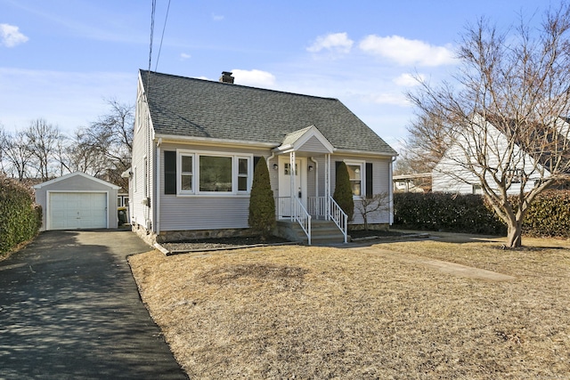 view of front of house with a garage, a chimney, aphalt driveway, roof with shingles, and an outbuilding