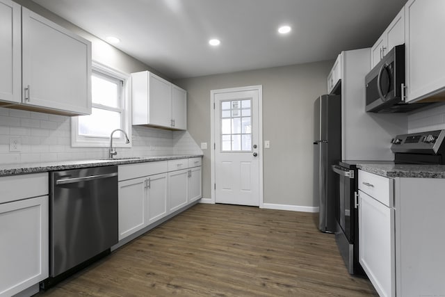 kitchen with stainless steel appliances, a sink, dark wood-style floors, and tasteful backsplash