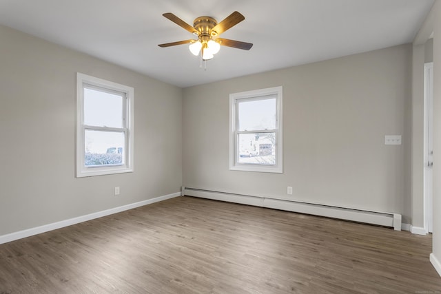 unfurnished room with a healthy amount of sunlight, baseboards, baseboard heating, and wood finished floors