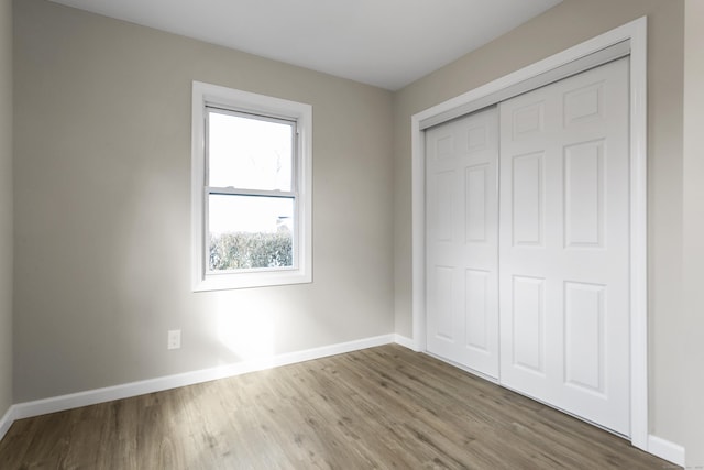 unfurnished bedroom with a closet, baseboards, and wood finished floors