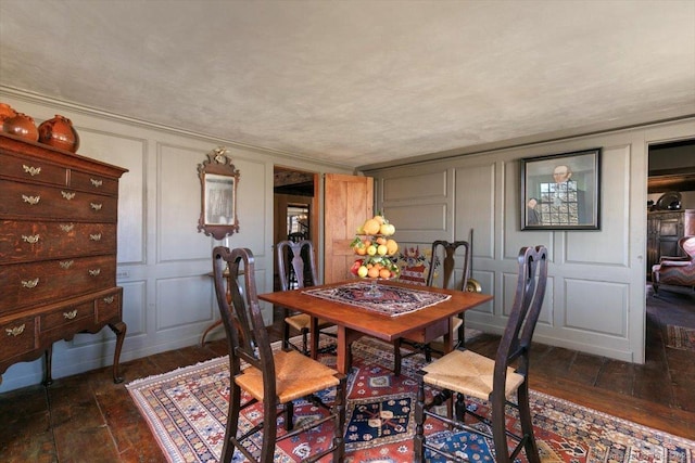 dining space featuring a decorative wall and dark wood-style floors