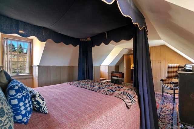 carpeted bedroom featuring lofted ceiling and wood walls