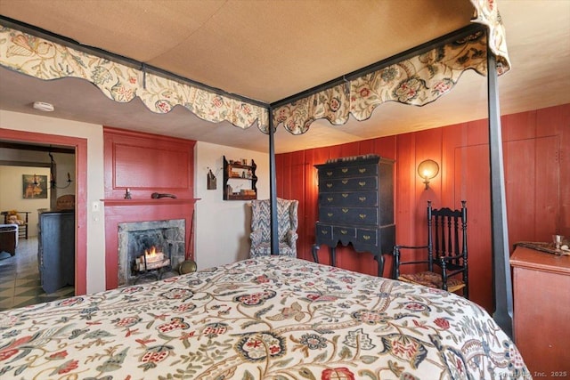 bedroom featuring wooden walls and a fireplace