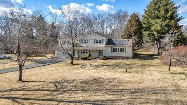 traditional home featuring driveway and roof mounted solar panels