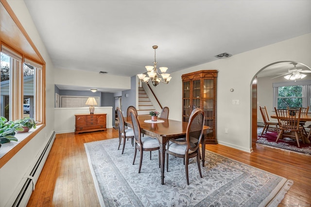 dining space with arched walkways, light wood finished floors, a baseboard radiator, and visible vents