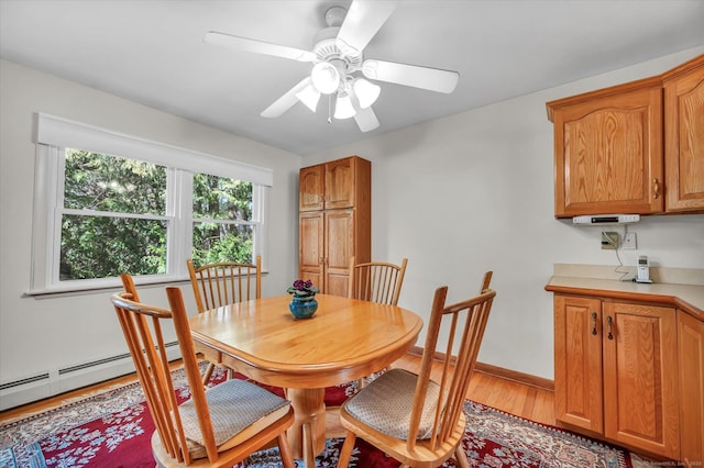 dining space with light wood-style floors, baseboard heating, ceiling fan, and baseboards