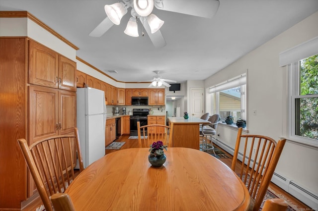 dining area with visible vents, baseboard heating, light wood-style flooring, and a ceiling fan