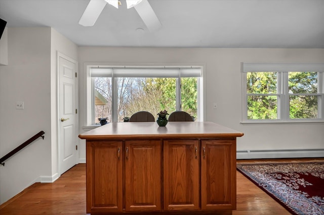 interior space featuring a baseboard heating unit, ceiling fan, wood finished floors, and baseboards