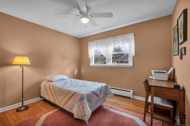 bedroom featuring a baseboard radiator, ceiling fan, baseboards, and wood finished floors