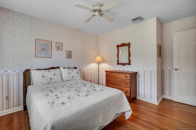 bedroom featuring wallpapered walls, baseboards, visible vents, and wood finished floors