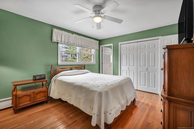 bedroom featuring a ceiling fan, light wood-style flooring, and multiple closets