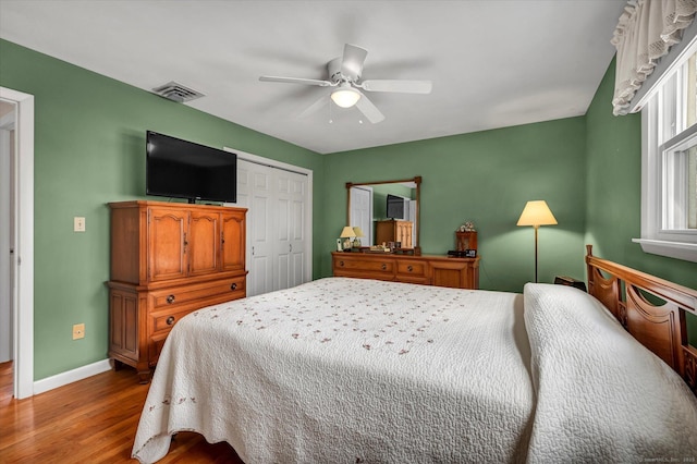 bedroom featuring wood finished floors, a ceiling fan, visible vents, baseboards, and a closet