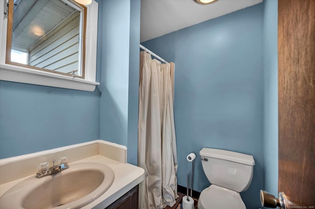 bathroom with curtained shower, vanity, and toilet