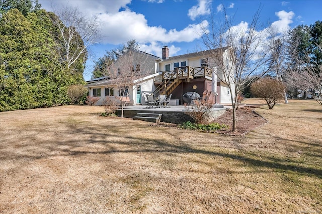 back of property featuring a deck, a patio, a yard, and a chimney