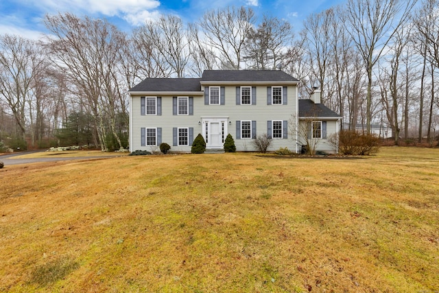 colonial house with a chimney and a front yard