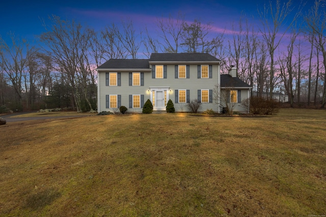 colonial inspired home with a lawn and a chimney