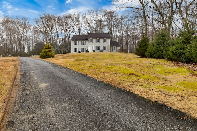 colonial inspired home featuring a front yard and a chimney