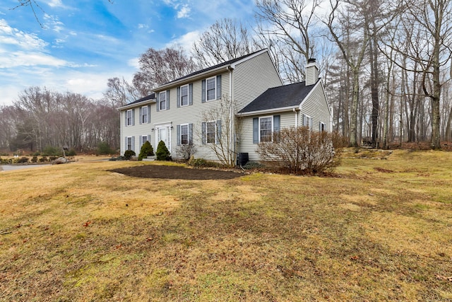 colonial home featuring central AC unit, a chimney, and a front lawn