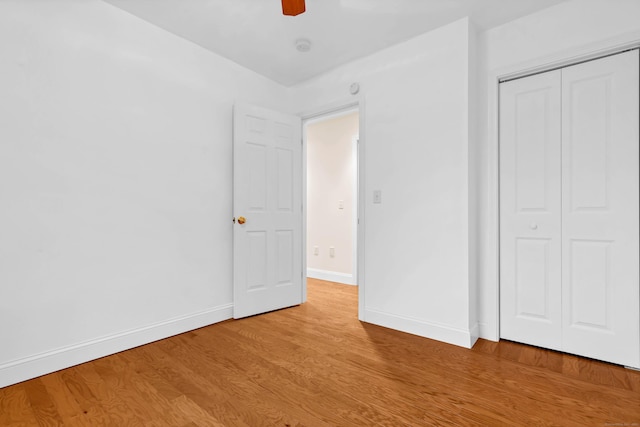 unfurnished bedroom featuring light wood-type flooring, baseboards, a closet, and ceiling fan