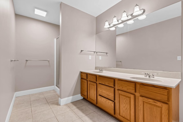 full bath featuring a shower stall, baseboards, double vanity, tile patterned floors, and a sink