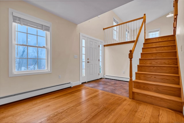 entryway featuring a baseboard heating unit, stairs, and wood finished floors