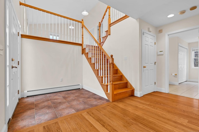 entrance foyer featuring wood finished floors, stairs, baseboards, and a baseboard radiator