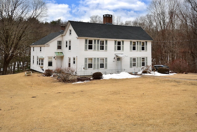 back of property featuring a shingled roof and a chimney