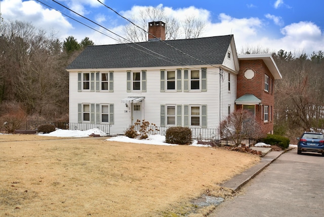 colonial-style house with a shingled roof and a chimney