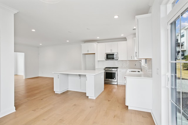 kitchen featuring a sink, appliances with stainless steel finishes, light wood-type flooring, a center island, and tasteful backsplash