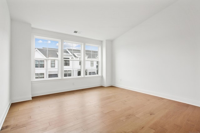 empty room with baseboards, visible vents, and light wood-style floors