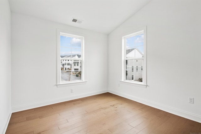 empty room with a healthy amount of sunlight, visible vents, baseboards, and wood finished floors