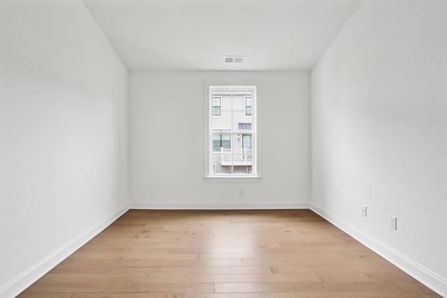 spare room with baseboards, visible vents, and light wood finished floors