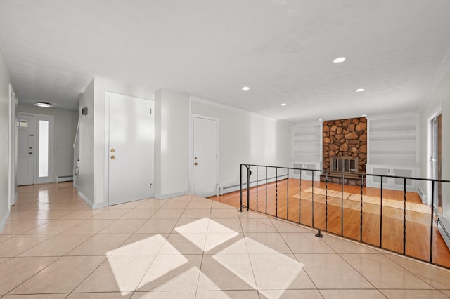 empty room featuring a baseboard heating unit, a fireplace, built in shelves, and light tile patterned floors