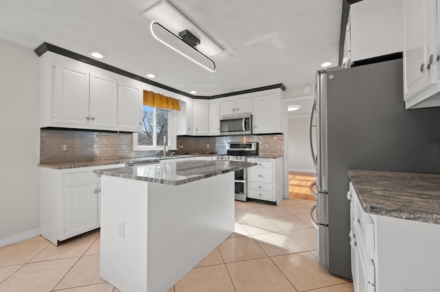 kitchen with stainless steel appliances, white cabinetry, a sink, and light tile patterned floors