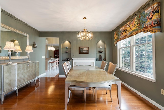 dining space with baseboards, ornamental molding, a chandelier, and wood finished floors