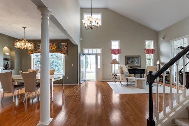 entrance foyer featuring a chandelier, hardwood / wood-style flooring, decorative columns, and stairs